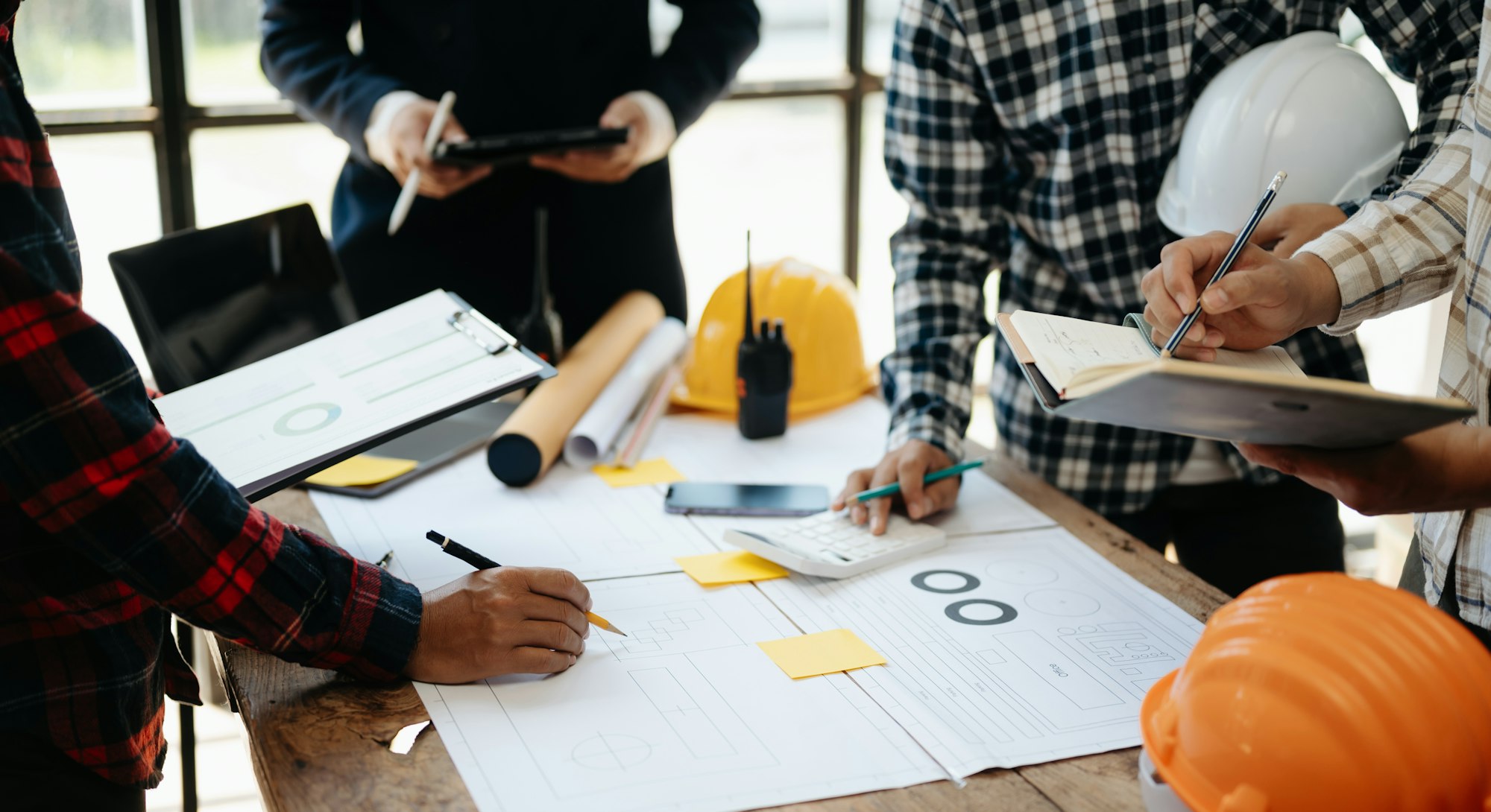 Engineer desk with object paper and tablet with blurry engineer teamwork hardworking